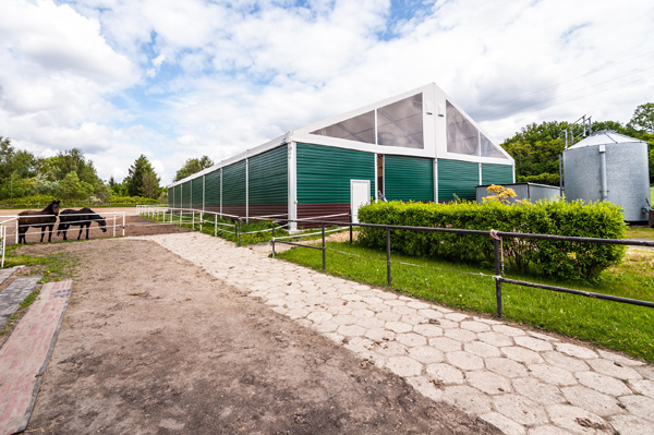 Pohled na jízdárnu s plechovým opláštěním a průhlednou střechou.