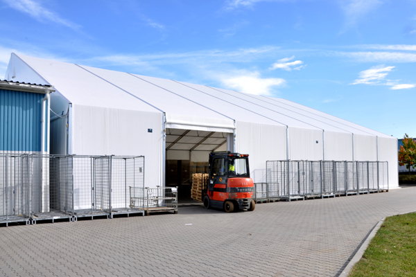 Vyskozdvižný vozík vjíždí do plachtové skladovací haly.